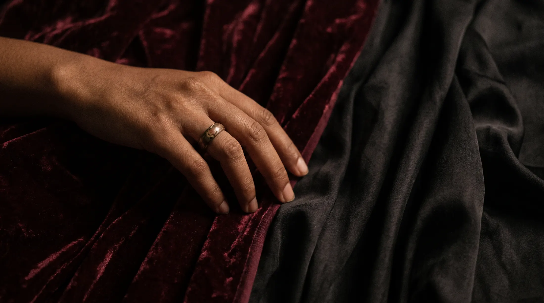 Hand over folds of burgundy velvet and black silk